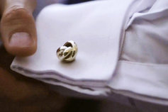 man buttoning up cufflinks
