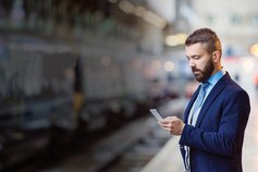 Man in train station platform looking at phone