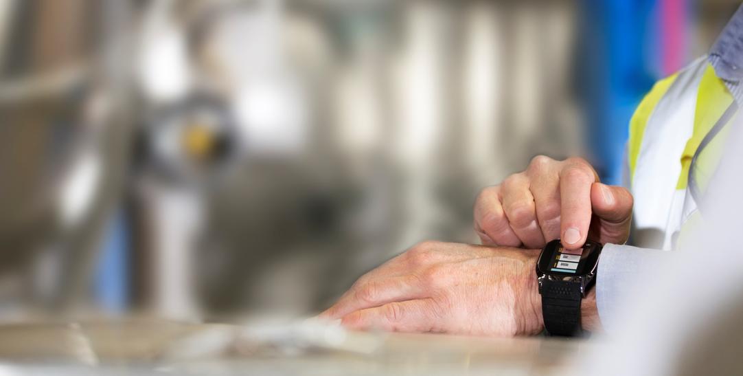 Man using smartwatch in industrial setting