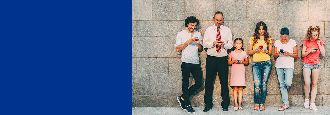 People young and middle aged standing against wall with phones in hand