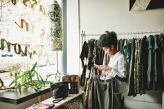Woman in shop holding clothes and phone