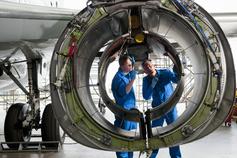Engineers inspecting engine casing of passenger jet in hangar