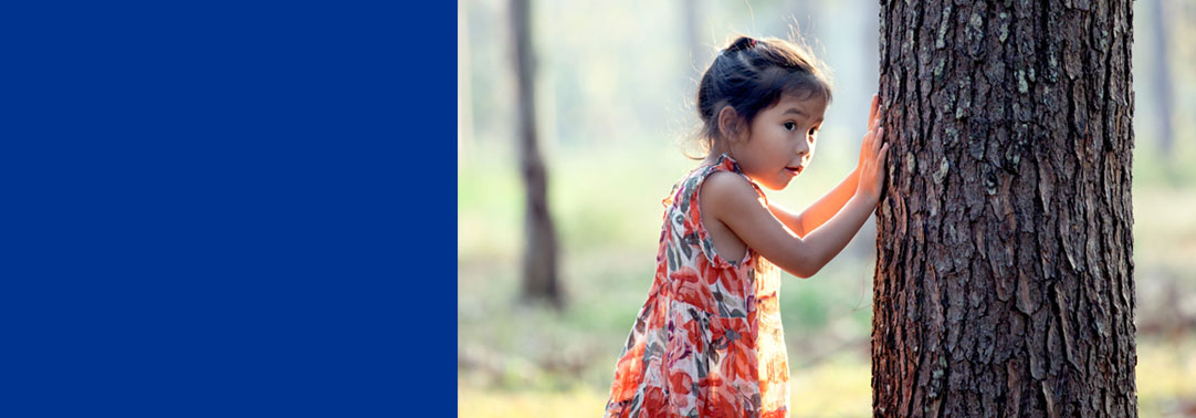 Young girl next to tree in forest