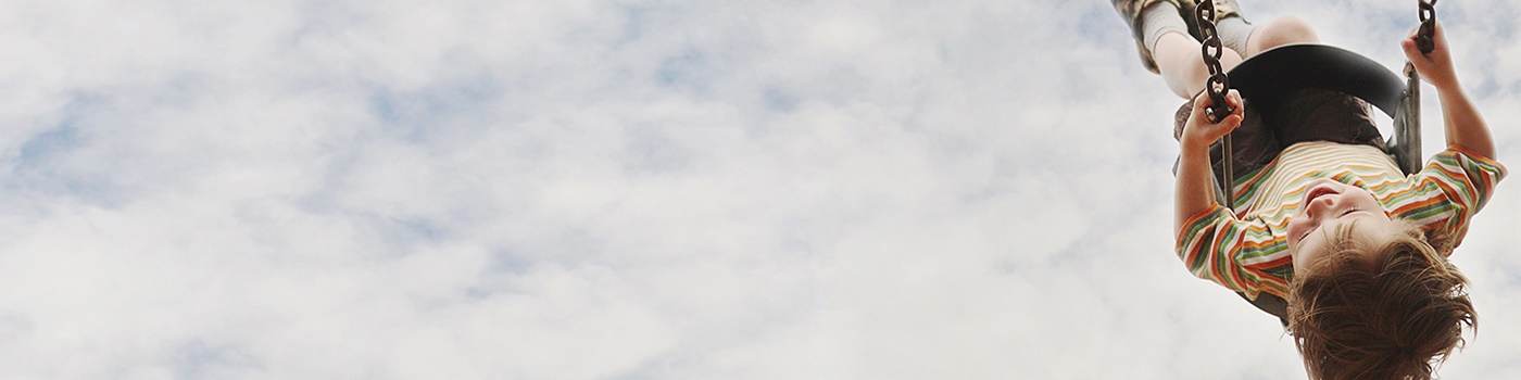Little boy swinging on a swing against sky and cloud background