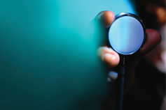 Hand holding stethoscope on green background