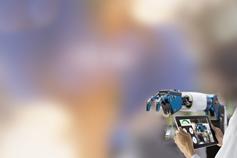 Hands holding tablet laptop against robot arm with blur background