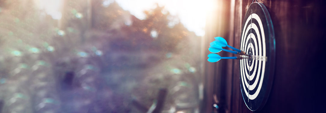 Side view of blue arrows on darts board at sunset