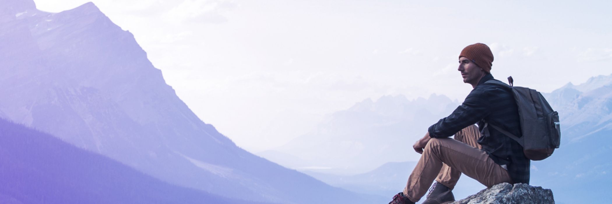 Un joven sentado en una roca con vistas al Lago Peyto.