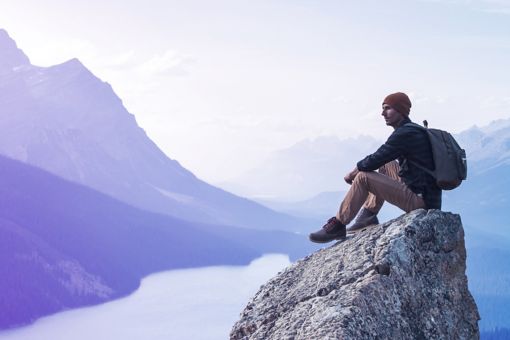 Un joven sentado en una roca con vistas al Lago Peyto.