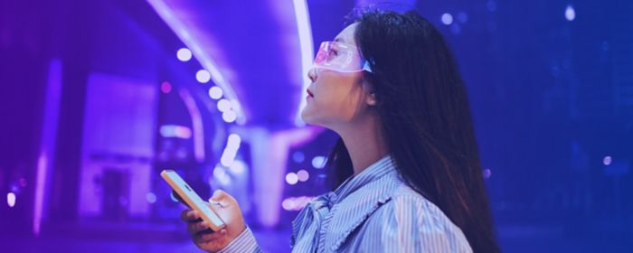 Joven mujer utilizando teléfono inteligente en un entorno futurista