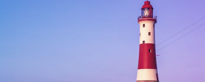 Faro de luz a la orilla del mar. El fondo es un degradado de purpura a azul cobalto