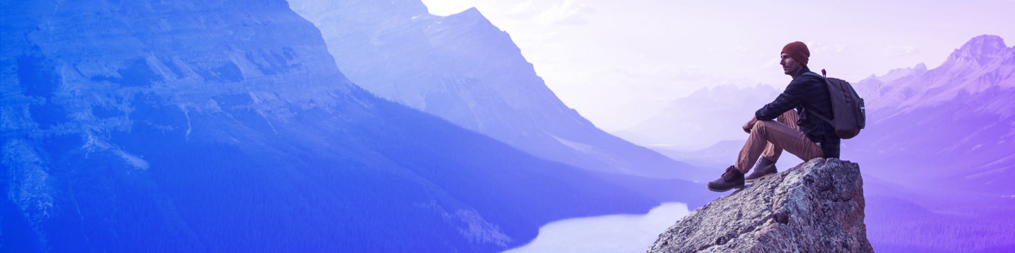 Un joven sentado en una roca con vistas al Lago Peyto.