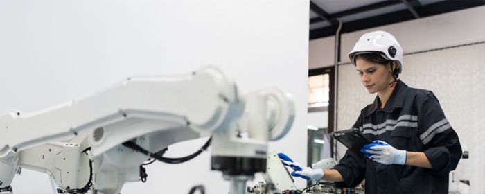 Una ingeniera controla el robot móvil autónomo o AMR en la sala de la academia de automatización de fabricación y robótica. Robot de IA de formación o mantenimiento de mujeres ingenieras