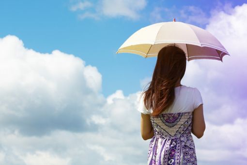 Woman with umbrella in front of clouds