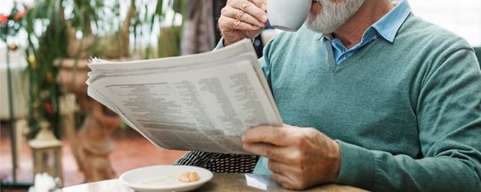 Mann trinkt Kaffee und liest Zeitung