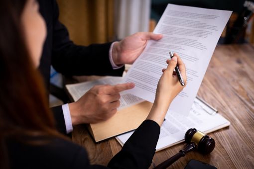 Two people are holding papers and pointing with a pen
