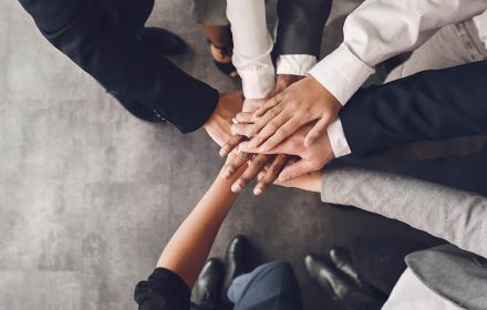 Business men and women putting hands together