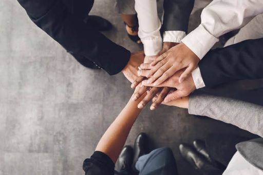 Business men and women putting hands together