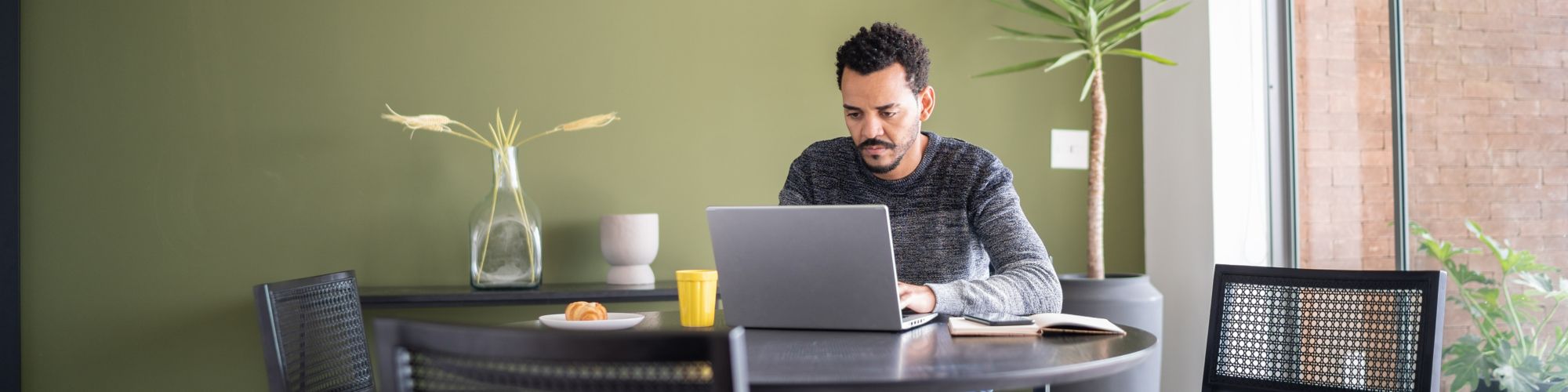 Hombre usando la computadora mientras desayuna