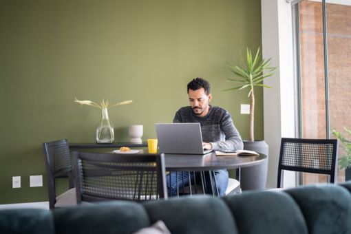 Hombre usando la computadora mientras desayuna