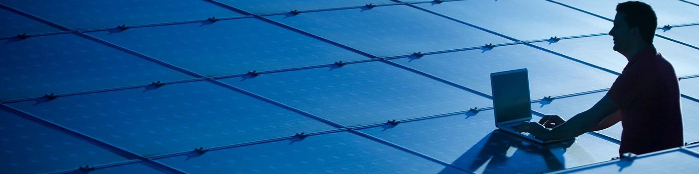 imagem de um home com um notebook entre placas de energia solar