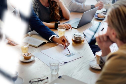 A group of people at a table, with tablets and papers on the table