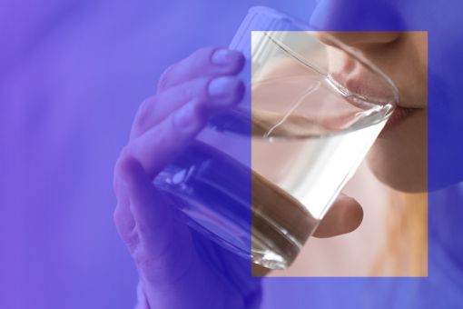 A woman drinking water in a glass.