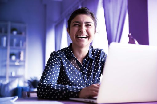 Mulher sorrindo utilizando um notebook
