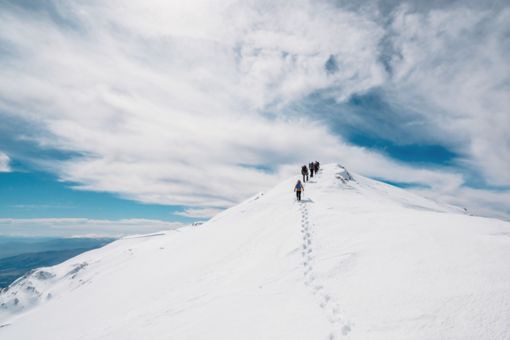 Folk der vandrer på bjerg med sne