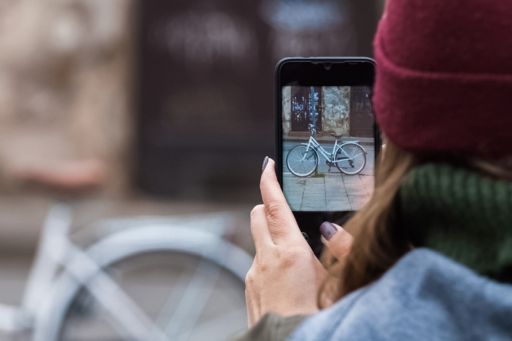 woman with mobile phone photographing bicycle