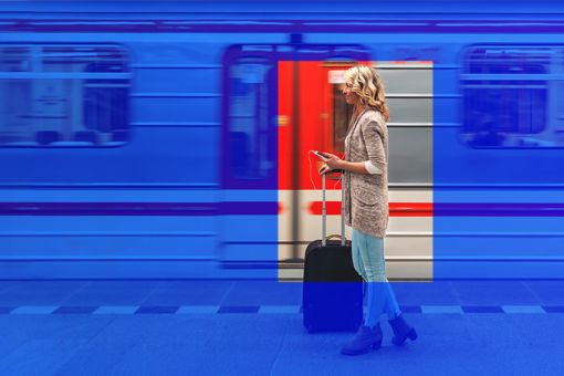 Lady holding suitcase standing outside moving train