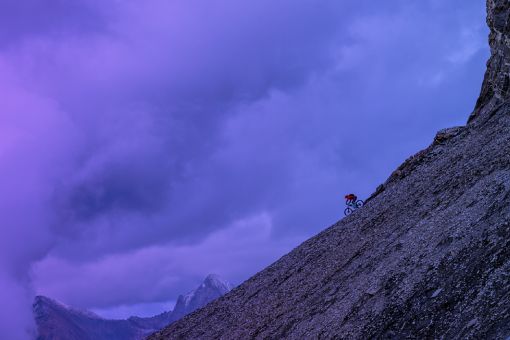 Fotografía de un hombre en la cima de una montaña con una bicicleta