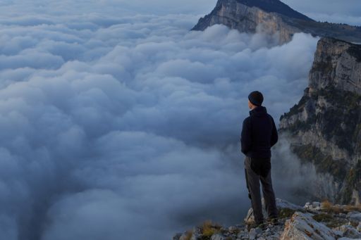man looking over the cloud top of mountain