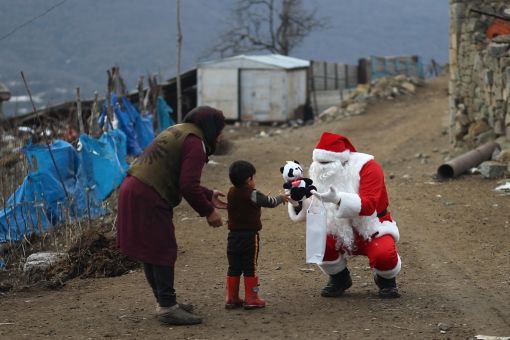 DASHKASAN, AZERBAIJAN - DECEMBER 25: A man dressed as Santa Claus walks through the village to deliver gifts on December 25, 2021 in Dashkasan, Azerbaijan. Although Christmas is not a national celebration in Azerbaijan, many see it as an opportunity to be charitable. Although Christmas is not a national celebration in Azerbaijan. (Photo by Aziz Karimov/Getty Images)