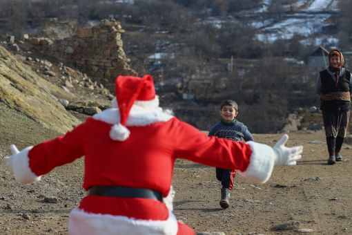 DASHKASAN, AZERBAIJAN - DECEMBER 25: A man dressed as Santa Claus walks through the village to deliver gifts on December 25, 2021 in Dashkasan, Azerbaijan. Although Christmas is not a national celebration in Azerbaijan, many see it as an opportunity to be charitable. Although Christmas is not a national celebration in Azerbaijan. (Photo by Aziz Karimov/Getty Images)