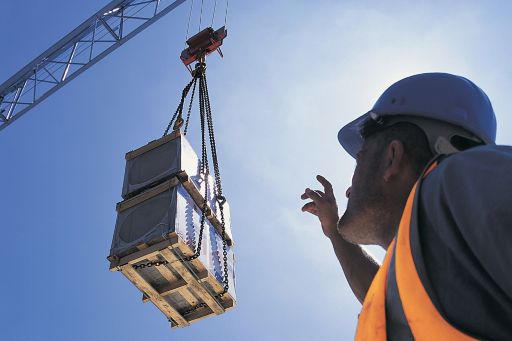 KPMG IFRS Newsletter: The Balancing Items publication cover image: a construction worker looks up at a crane moving a heavy load.