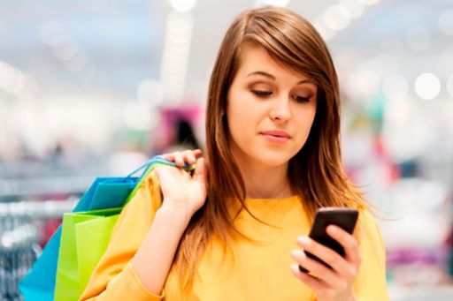 KPMG 'New revenue standard: A clearer view of IFRS 15' publication image: Woman looking at a smartphone while carrying shopping bags.