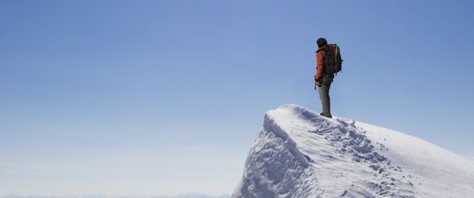 KPMG 'The future of IFRS' topic image: Climber on summit of snow capped mountain.