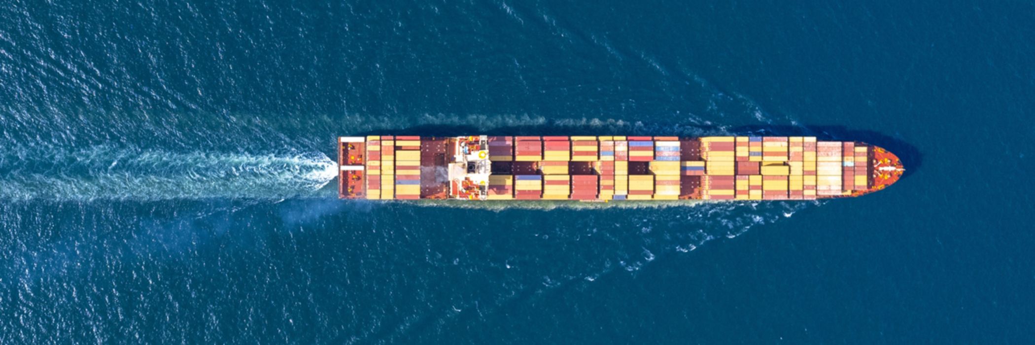 A cargo ship loaded with container sailing on a calm blue sea