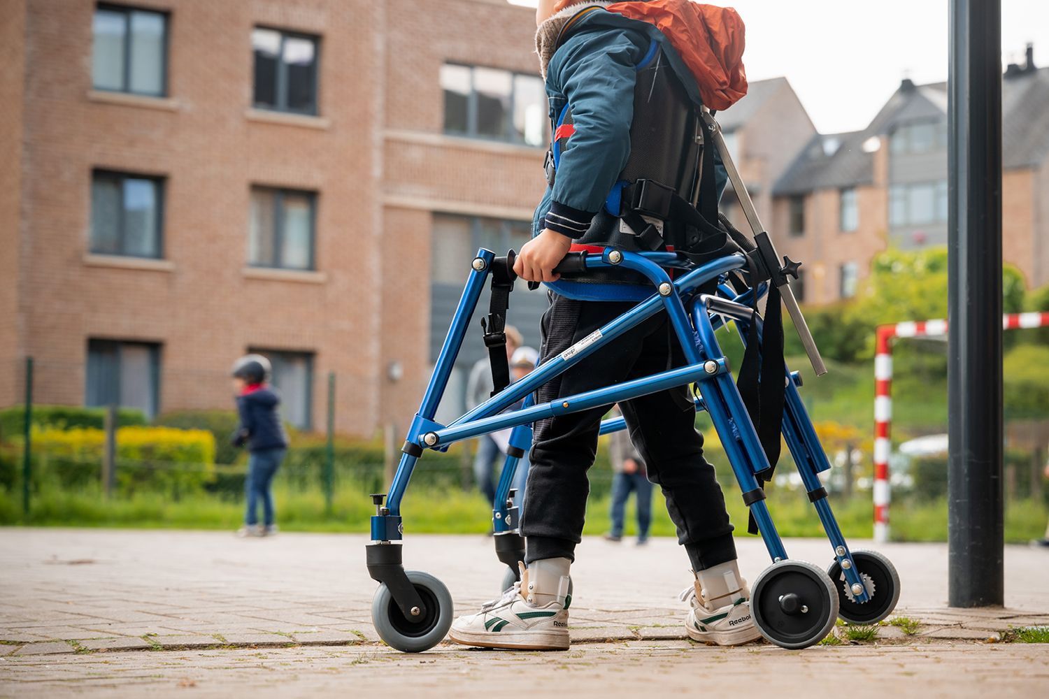 child outside in the playground with a blue wheelchair