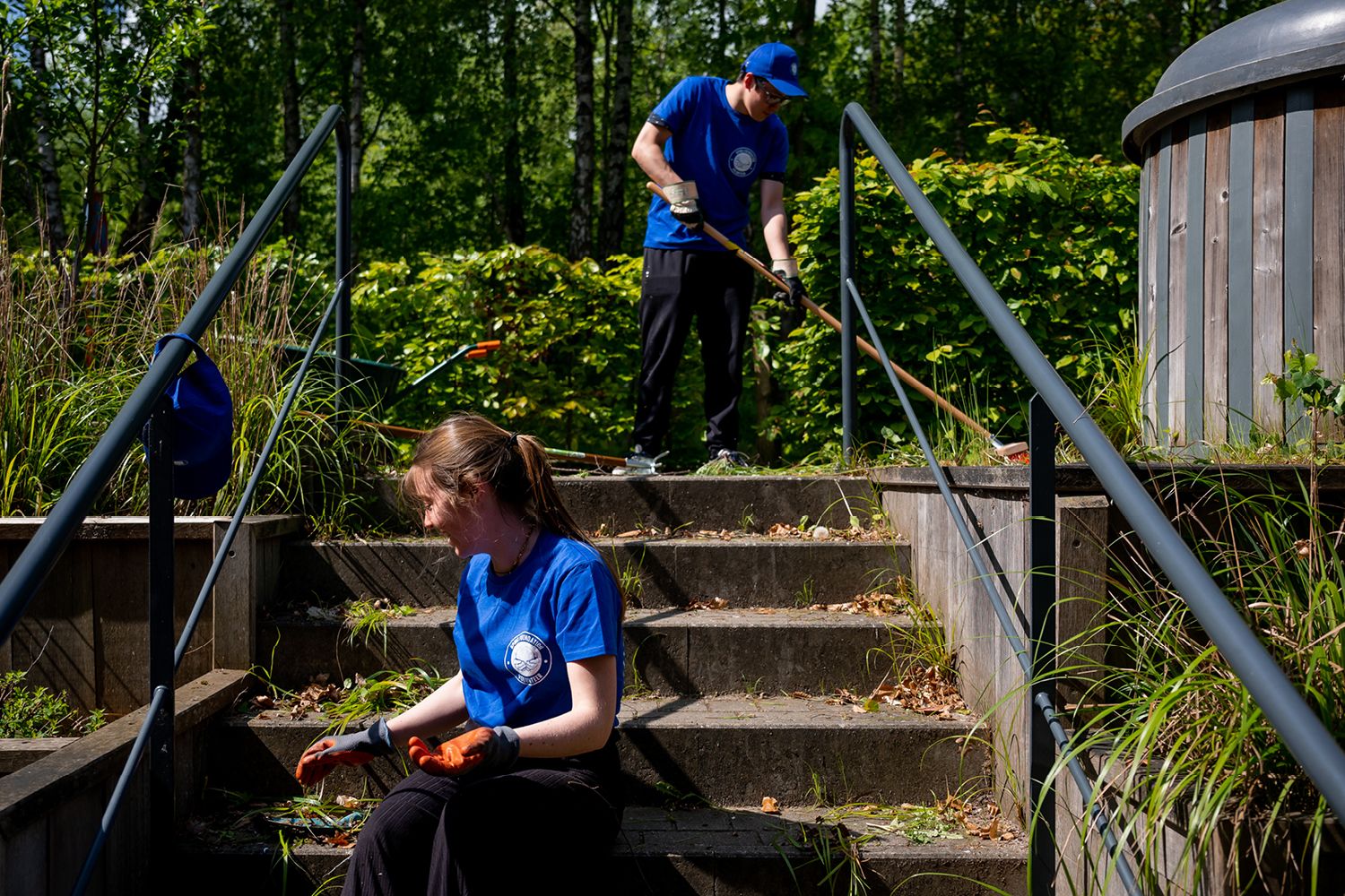 two volunteers clear weeds from the stairs