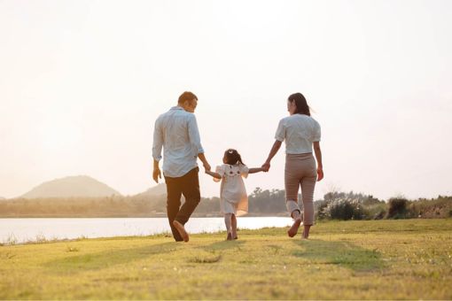 Happy family holding hands walking by the water