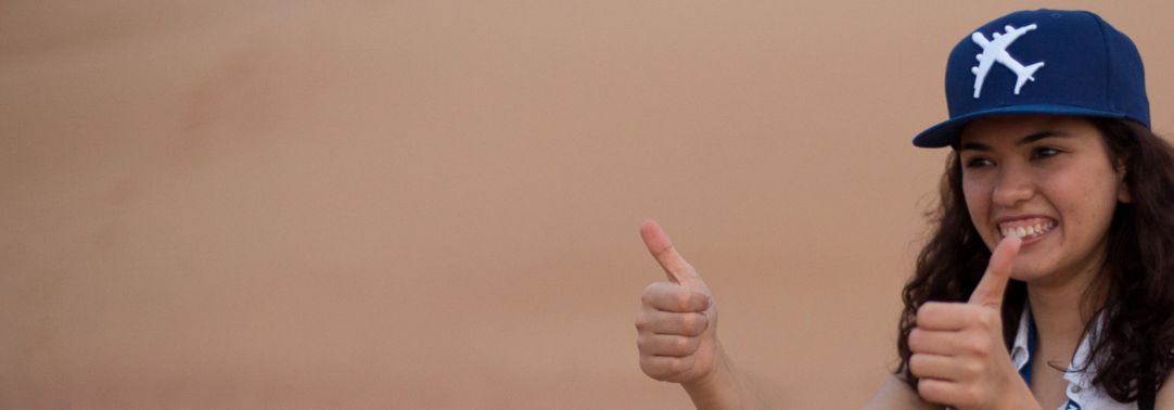 woman wearing baseball cap giving the thumbs up