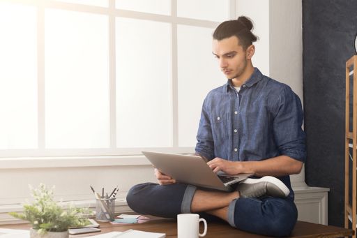 Man sitting on desk working on laptop from home