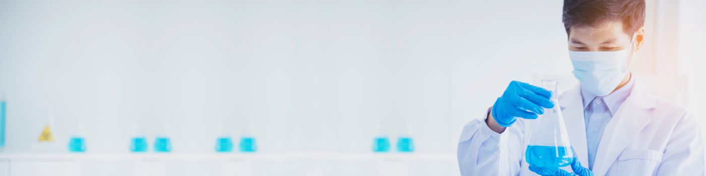 Male scientist examining beaker with blue liquid