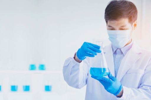 Male scientist examining beaker with blue liquid