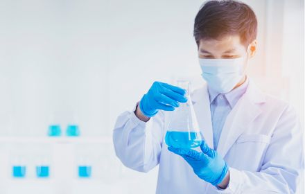 Male scientist examining beaker with blue liquid