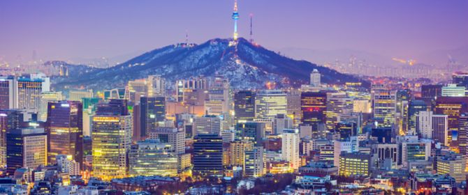 vista de uma cidade na Korea e ao fundo da cidade um monte com uma torre de telecomunicações
