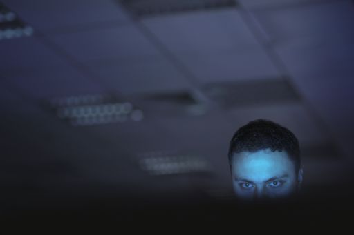 Imagem de homem olhando laptop no escuro