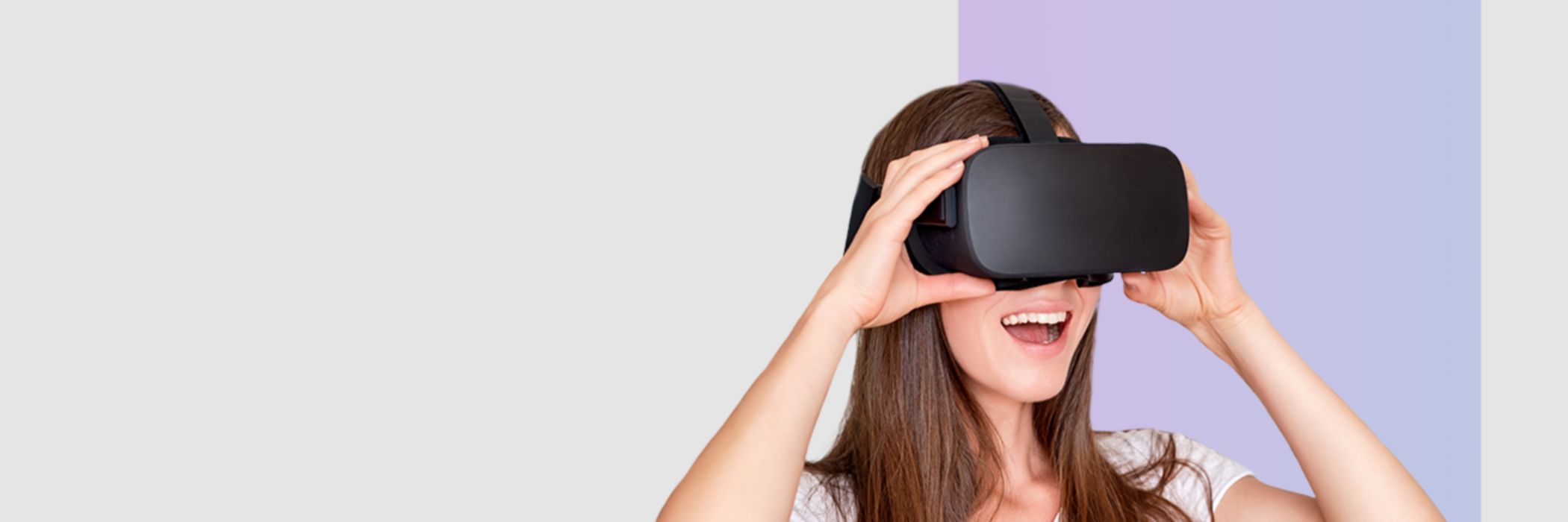 Frau mit virtuell Reality Brille steht vor grauem Hintergrund.